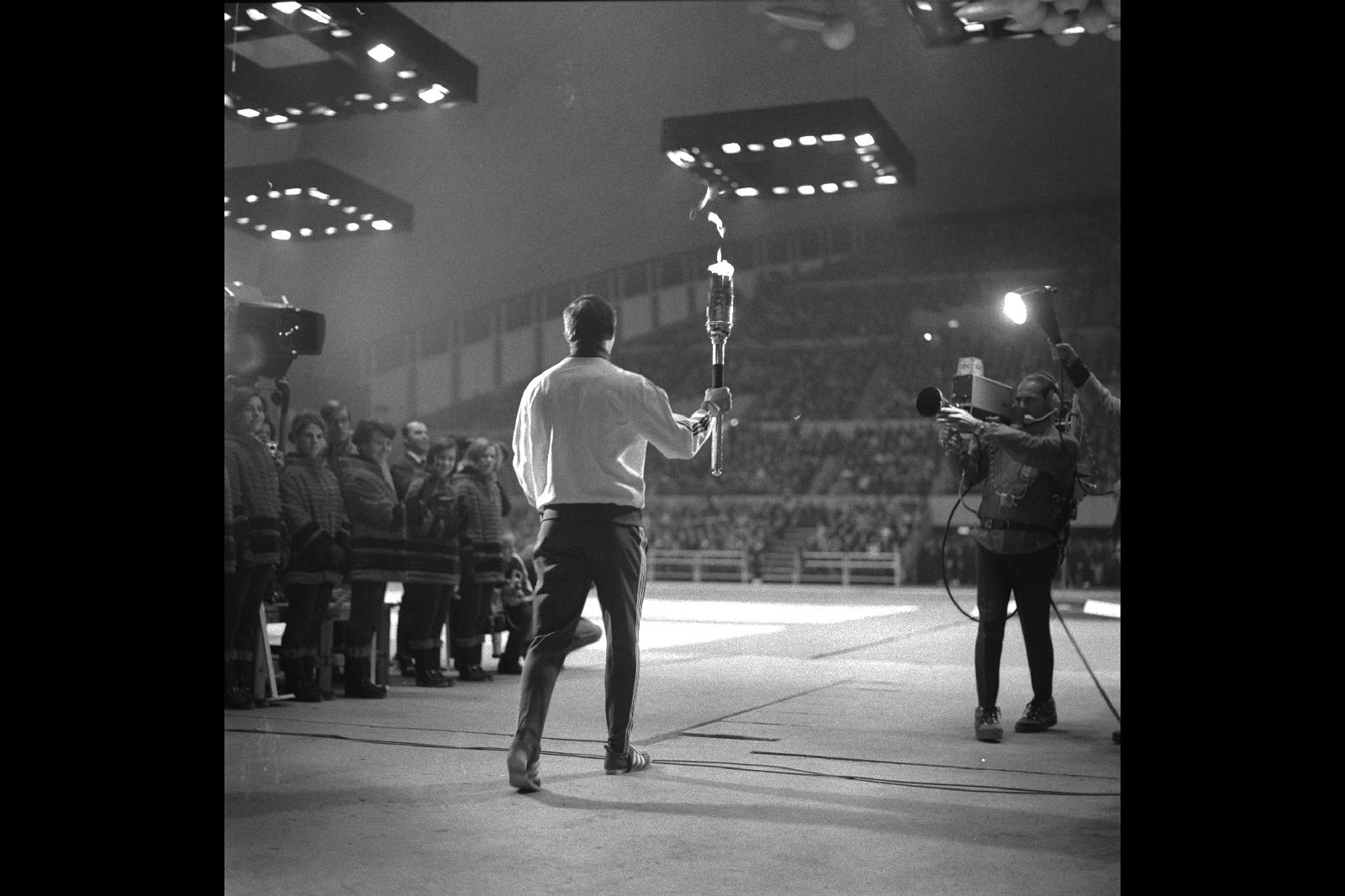 JO Hiver Grenoble 1968, Cérémonie de clôture - Daniel ROBIN (FRA), porteur de la torche olympique, entre dans la patinoire olympique.
